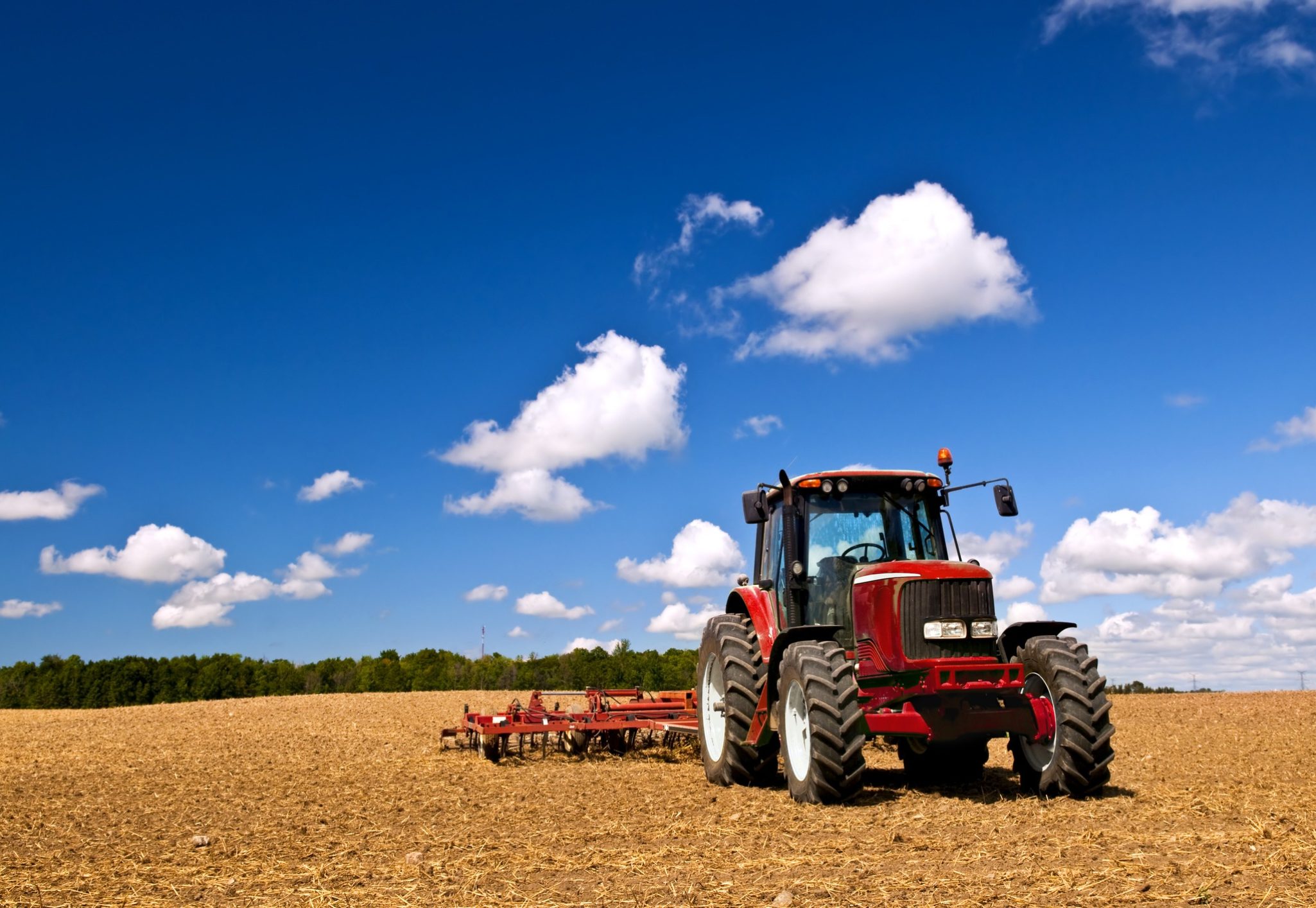 Small scale farming with tractor and plow in field