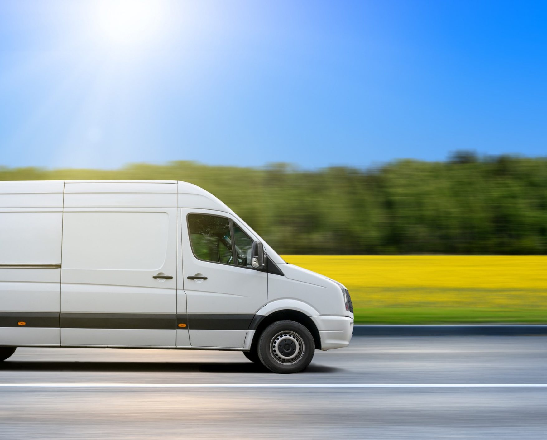 White delivery van drives on asphalt road in the countryside.