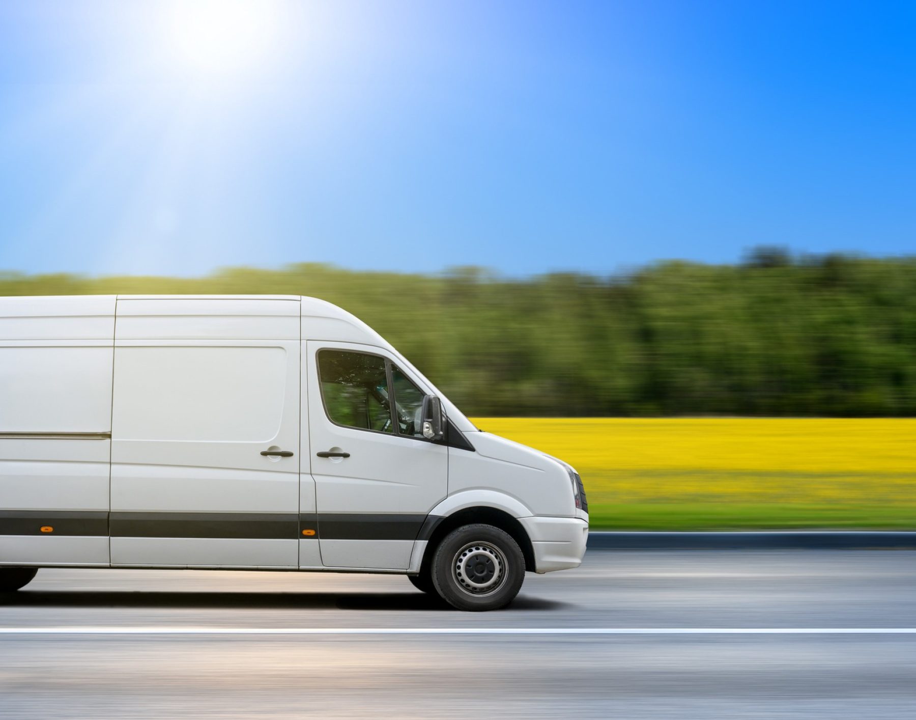 White delivery van drives on asphalt road in the countryside.